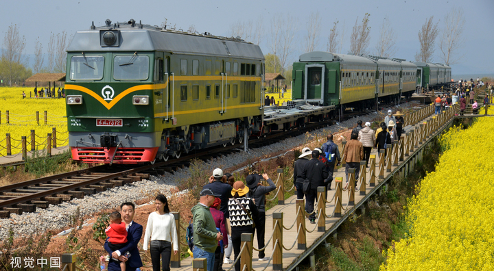 2023年2月23日，昆明，晋宁沙堤余家沟下村千亩油菜花盛放灿烂春色，开往春天的绿皮小火车“穿行”金色花海绘就乡村振兴新画卷，美不胜收的花田春景令游人陶醉其中。

