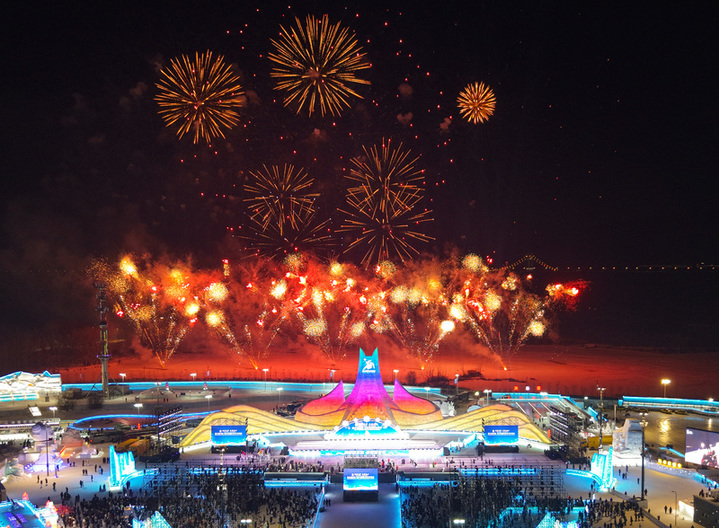 2025年1月5日，第41届中国·哈尔滨国际冰雪节在哈尔滨冰雪大世界盛大启幕，在冰雪大世界园区，礼花升空朵朵绽放与无人机表演同台竞技，市民游客在园区里拍照、打滑梯充分体验着哈尔滨冰雪乐趣。来源：视觉中国