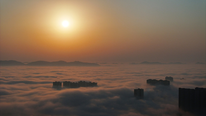 2025年1月10日，湖南省邵阳市洞口县，雪后初晴，太阳升起，晨光中云海波动，村庄、城市犹如海市蜃楼，蔚为壮观。