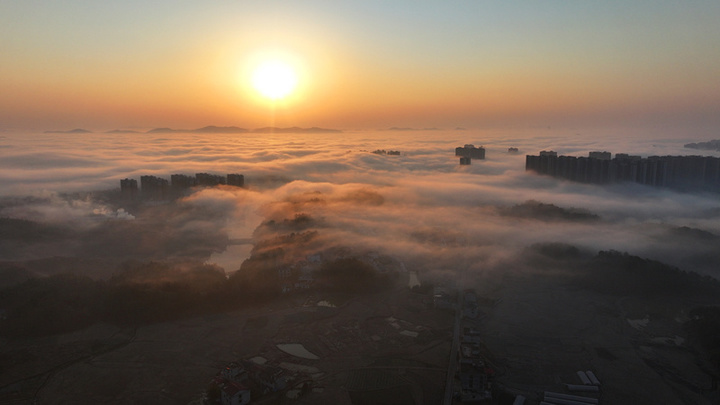 2025年1月10日，湖南省邵阳市洞口县，雪后初晴，太阳升起，晨光中云海波动，村庄、城市犹如海市蜃楼，蔚为壮观。李世近/视觉中国
