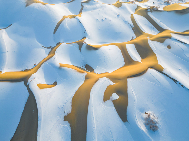 2025年1月15日，新疆巴州尉犁县，塔克拉玛干沙漠披上了银装，“沙海”变“雪海”， 沙丘的轮廓在雪的覆盖下显得更加柔和，高低起伏的沙脊与洁白的雪层构成了独特的纹理，宛如大自然精心绘制的壮美画卷。