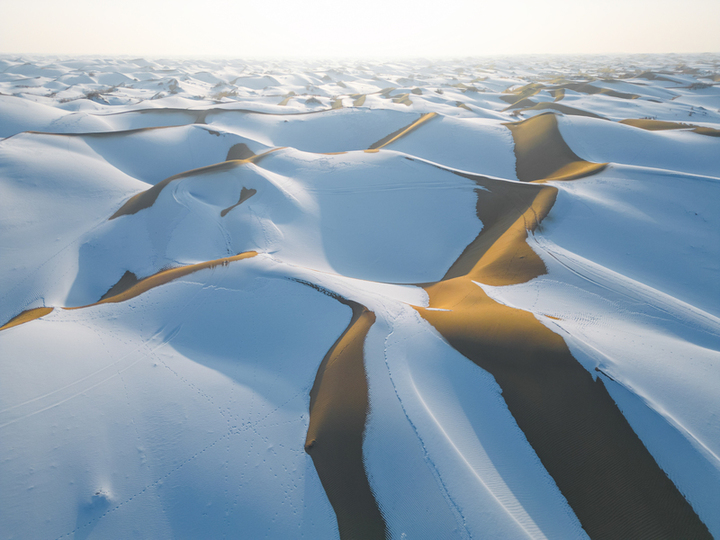 2025年1月15日，新疆巴州尉犁县，塔克拉玛干沙漠披上了银装，“沙海”变“雪海”， 沙丘的轮廓在雪的覆盖下显得更加柔和，高低起伏的沙脊与洁白的雪层构成了独特的纹理，宛如大自然精心绘制的壮美画卷。