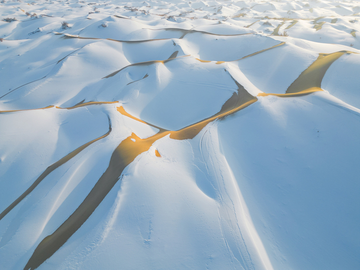 2025年1月15日，新疆巴州尉犁县，塔克拉玛干沙漠披上了银装，“沙海”变“雪海”， 沙丘的轮廓在雪的覆盖下显得更加柔和，高低起伏的沙脊与洁白的雪层构成了独特的纹理，宛如大自然精心绘制的壮美画卷。