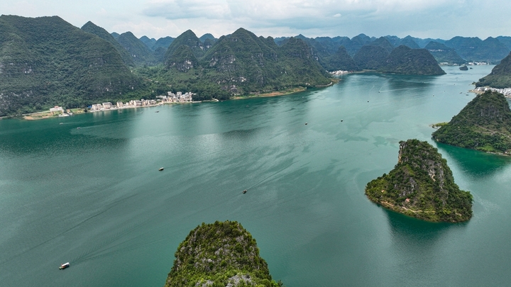 在广西壮族自治区靖西市渠洋镇东风村，波光粼粼的水面与民居、游船、群山相映成景，构成一幅生态宜居的美丽乡村画卷。