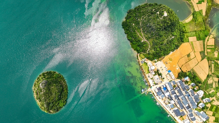 在广西壮族自治区靖西市渠洋镇东风村，波光粼粼的水面与民居、游船、群山相映成景，构成一幅生态宜居的美丽乡村画卷。