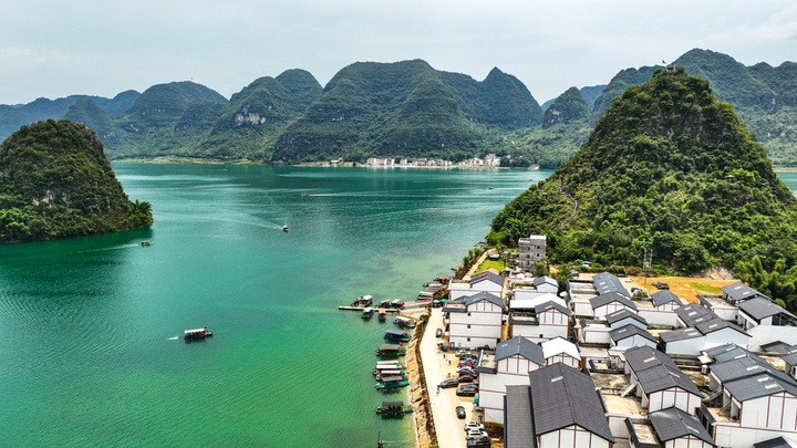 在广西壮族自治区靖西市渠洋镇东风村，波光粼粼的水面与民居、游船、群山相映成景，构成一幅生态宜居的美丽乡村画卷。