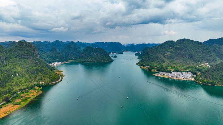 在广西壮族自治区靖西市渠洋镇东风村，波光粼粼的水面与民居、游船、群山相映成景，构成一幅生态宜居的美丽乡村画卷。