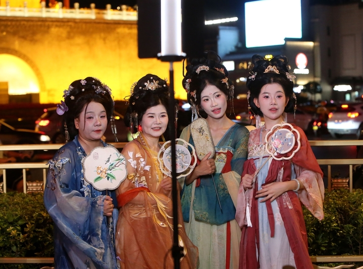 2025年8月14日晚上，陕西省西安市，无数游客身着不同风格的服饰，化着精致的妆容，带着形形色色的道具在西安钟楼下拍照，形成古城西安独特的美丽风景。来源：尚洪涛/IC photo

