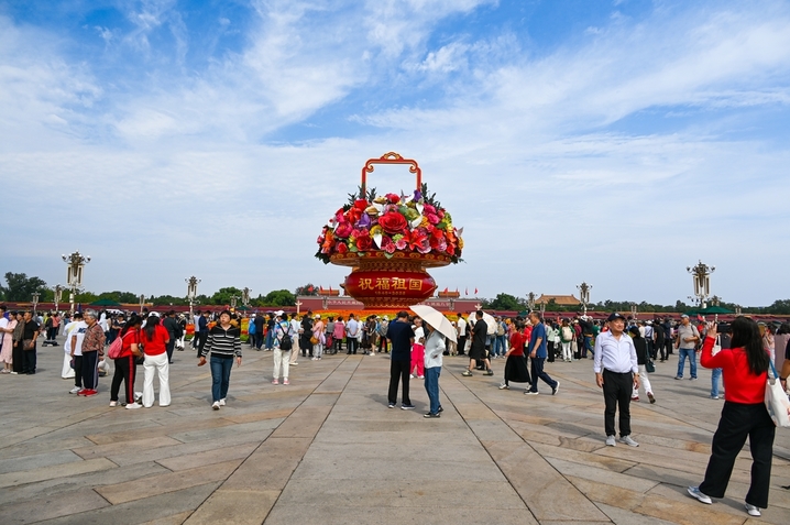 2025年9月26日，北京，天安门广场，游客在庆祝国庆节的花篮前拍照打卡。