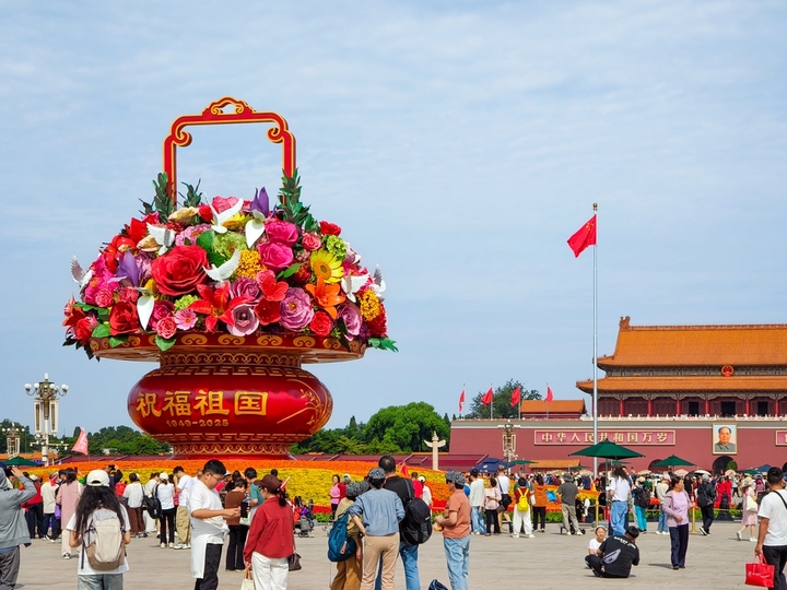 2025年9月26日，北京，天安门广场，游客在庆祝国庆节的花篮前拍照打卡。