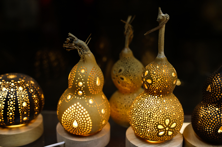 2025年9月26日晚，在新疆阿克苏市老街，非遗传承人木扎帕尔·艾斯卡尔给游客展示他创作的葫芦绘画作品。木扎帕尔出生在绘画世家，儿时便跟随爷爷、父亲学习在葫芦上绘画、雕刻，多年来，他凭借炉火纯青的技艺，让普通的葫芦焕发新生。