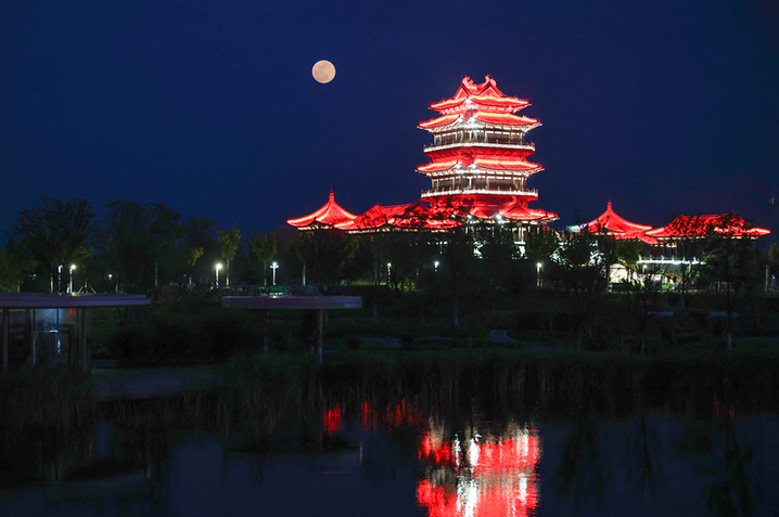 2025年10月6日，江苏连云港园博园秦东阁与夜空满月同框。
