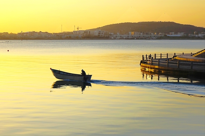 2025年12月8日，山东青岛，日出时分，素有“海上西湖”美誉的唐岛湾波光粼粼，水天一色，如画美景令人心旷神怡。