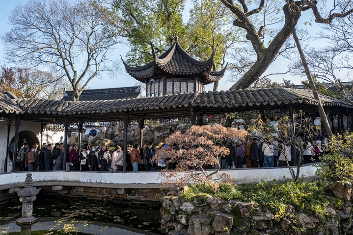 2025年12月9日，江苏苏州拙政园中的宜两亭重新对外开放，凭借其独特的冰梅纹窗棂吸引大量游客排长队观赏。一白/IC photo
