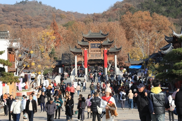 2025年12月9日 ，江苏南京栖霞山枫叶现已进入最佳观赏期，呈现出深红与飘丹交织的浪漫景象。偶遇景区给树木浇水，水雾透过光线穿过水雾形成的光柱营造出梦幻的丁达尔效应，与漫山遍野的红叶相映成趣，尤为迷人。
 