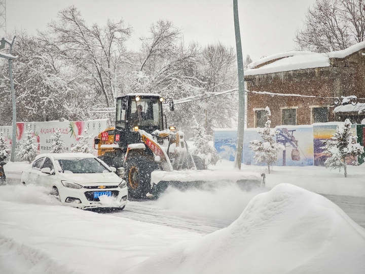 2025年12月10日，新疆阿勒泰，新疆阿勒泰降大雪，铲雪车和工人紧急清扫道路，保障市民出行安全。