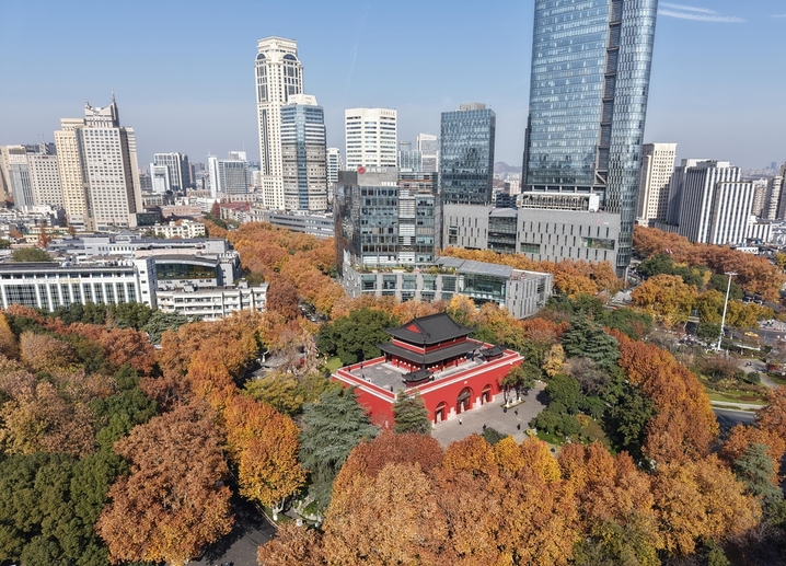 2025年12月9日，南京秋高气爽，鼓楼公园秋色斑斓，周边的树木各色交织，与古朴、砖红色的古建筑相映，如一幅画卷，美不胜收！