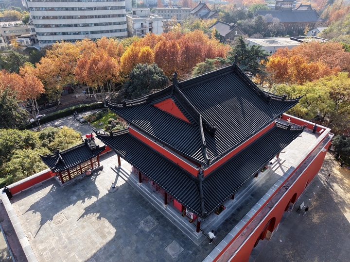 2025年12月9日，南京秋高气爽，鼓楼公园秋色斑斓，周边的树木各色交织，与古朴、砖红色的古建筑相映，如一幅画卷，美不胜收！雨田/IC photo