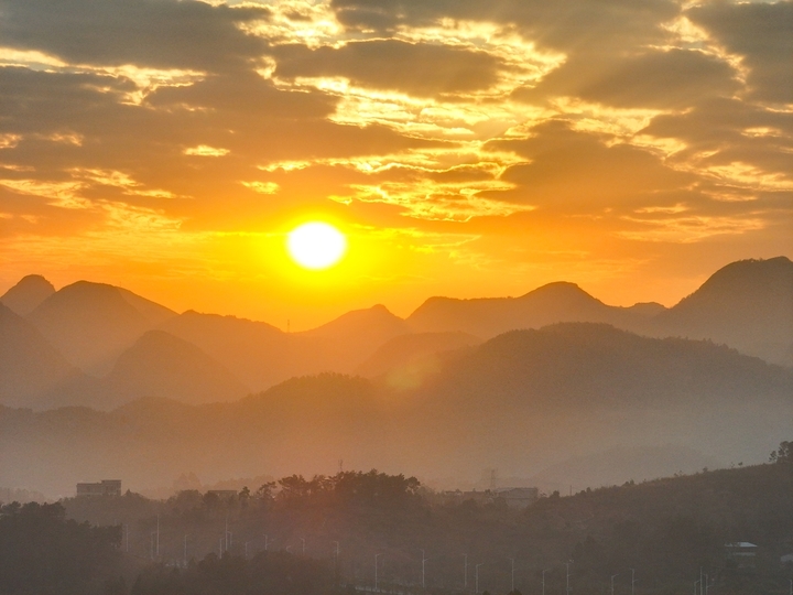 2025年12月15日，广西桂林，太阳从远处的山顶渐渐升起，温暖的阳光照耀着远处的山峦和村庄，映红了湘江，江面上的小舟在收拾渔获，码头广场还有晨练的瑜伽…冬日暖阳晨景美不胜收。