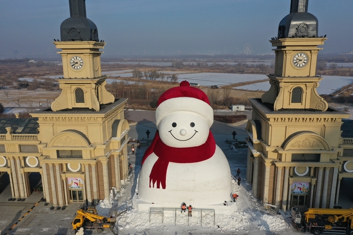 2025年12月15日，黑龙江省哈尔滨市，道里区群力江畔音乐广场上的网红大雪人制作已基本完成，吸引了许多游客前来打卡拍照。 今年的网红大雪人身高19米、长14米、宽11米，比往年高了1米，用雪量增加了1200立方米，总用雪量超3000立方米，达到历年之最。