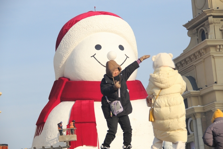 2025年12月15日，黑龙江省哈尔滨市，道里区群力江畔音乐广场上的网红大雪人制作已基本完成，吸引了许多游客前来打卡拍照。 今年的网红大雪人身高19米、长14米、宽11米，比往年高了1米，用雪量增加了1200立方米，总用雪量超3000立方米，达到历年之最。来源：小刘/IC photo
