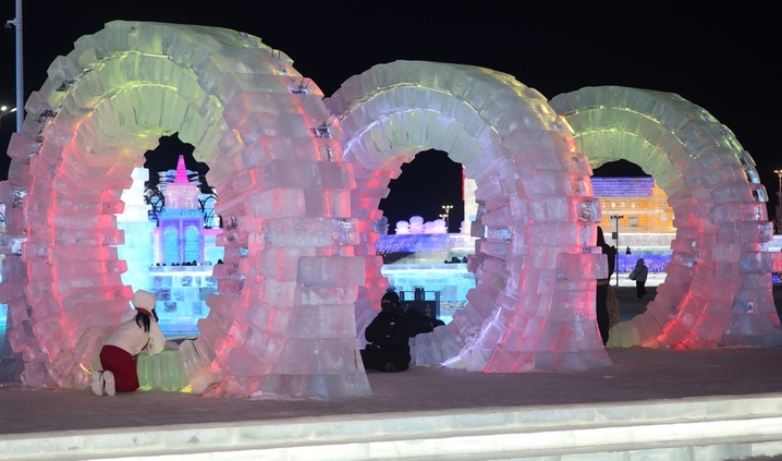 2025年12月20日，黑龙江省哈尔滨市，第二十七届哈尔滨冰雪大世界园区内，梦幻城堡景观区成为冬日焦点。这座最高处达24米的冰建奇观，以13200立方米晶莹剔透的冰堆砌而成，在寒风中闪耀着童话般的光泽。特别设计的圆形打卡点宛如天然画框，吸引众多女游客驻足留影。当人们端坐其间，仿佛置身于冰雪编织的梦境，每一个角落都散发着童话书里才有的浪漫气息，共同构筑起一个晶莹剔透的冰雪乌托邦。