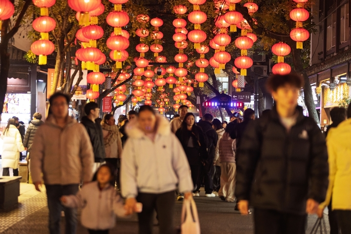 2025年12月30日，江苏南京，人们在夫子庙景区红灯笼下夜游。新年临近，南京夫子庙景区被大红灯笼装扮一下，红红火火迎新年。来源：IC photo