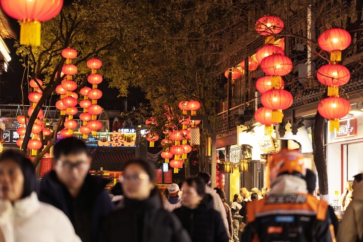 2025年12月30日，江苏南京，人们在夫子庙景区红灯笼下夜游。新年临近，南京夫子庙景区被大红灯笼装扮一下，红红火火迎新年。