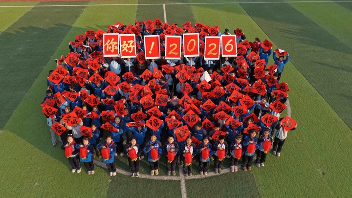 2025年12月26日，在山东省聊城市茌平区贾寨镇耿店新村小学，百名小学生手拿福字、红灯笼、手举“你好！2026”字样的牌子喜迎2026年新年元旦的到来（无人机照片）。