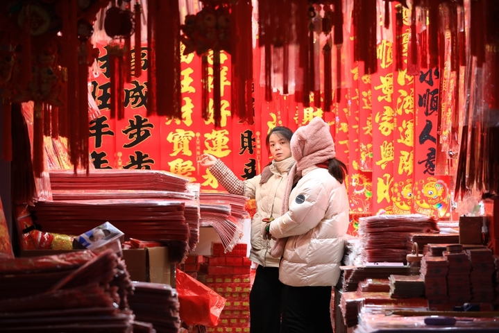 2025年12月27日，江苏省淮安市汇通小商品市场内市民选购红灯笼等新年饰品。元旦将至，春节也不远了，淮安市汇通小商品市场贩售年节装饰品的商家们陆续撤换下日常产品，沿街铺面放眼望去，是一片火红的色彩。