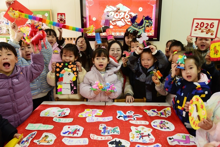 2025年12月29日，江苏省镇江市，解放路幼儿园，江苏大学志愿者和小朋友一起展示制作的迎新年主题手工作品。