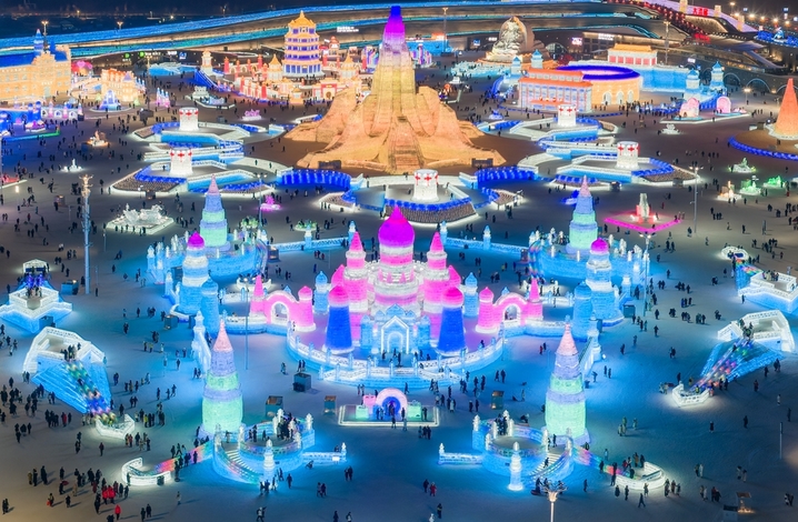 2026年1月5日，正值小寒节气，黑龙江省哈尔滨市，哈尔滨冰雪大世界冰雪节启幕，夜幕下，烟花腾空绽放，流光溢彩映亮冰雕玉砌的世界；无人机编队凌空起舞，变幻出骏马、雪花等灵动造型，各式冰雕晶莹剔透，5万游客驻足观赏拍照。
