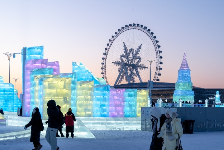 2026年1月5日，正值小寒节气，黑龙江省哈尔滨市，哈尔滨冰雪大世界冰雪节启幕，夜幕下，烟花腾空绽放，流光溢彩映亮冰雕玉砌的世界；无人机编队凌空起舞，变幻出骏马、雪花等灵动造型，各式冰雕晶莹剔透，5万游客驻足观赏拍照。
