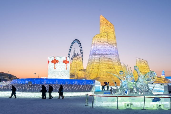 2026年1月5日，正值小寒节气，黑龙江省哈尔滨市，哈尔滨冰雪大世界冰雪节启幕，夜幕下，烟花腾空绽放，流光溢彩映亮冰雕玉砌的世界；无人机编队凌空起舞，变幻出骏马、雪花等灵动造型，各式冰雕晶莹剔透，5万游客驻足观赏拍照。
