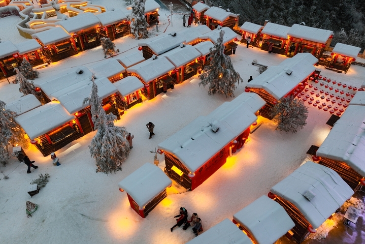 1月7日晚，贵州省六盘水市，游客在“南国雪乡”项目内游玩。该项目凭借梅花山滑雪场的核心优势，以“厚雪压木屋、红灯映炊烟”为设计理念打造，让南方民众邂逅地道雪乡风情。（无人机照片）  