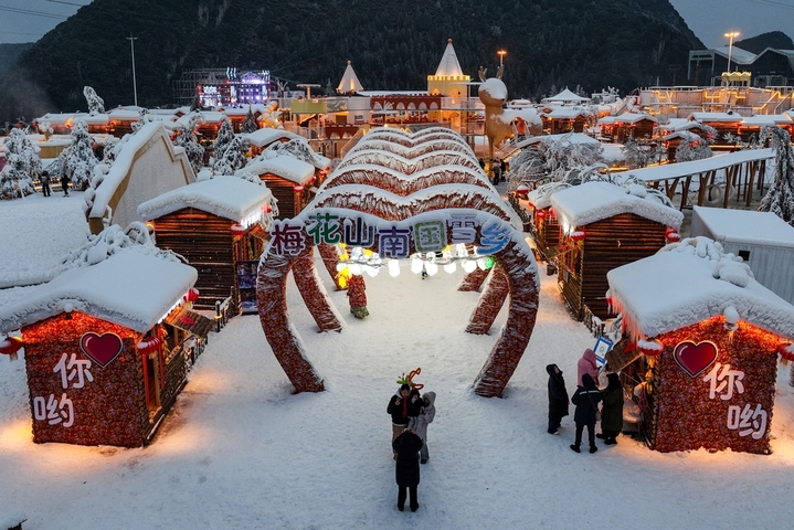 1月7日晚，贵州省六盘水市，游客在“南国雪乡”项目内游玩。该项目凭借梅花山滑雪场的核心优势，以“厚雪压木屋、红灯映炊烟”为设计理念打造，让南方民众邂逅地道雪乡风情。（无人机照片）  
