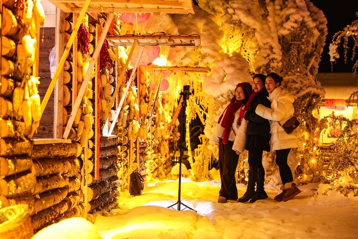 1月7日晚，贵州省六盘水市，游客在“南国雪乡”项目内游玩。该项目凭借梅花山滑雪场的核心优势，以“厚雪压木屋、红灯映炊烟”为设计理念打造，让南方民众邂逅地道雪乡风情。（无人机照片）  