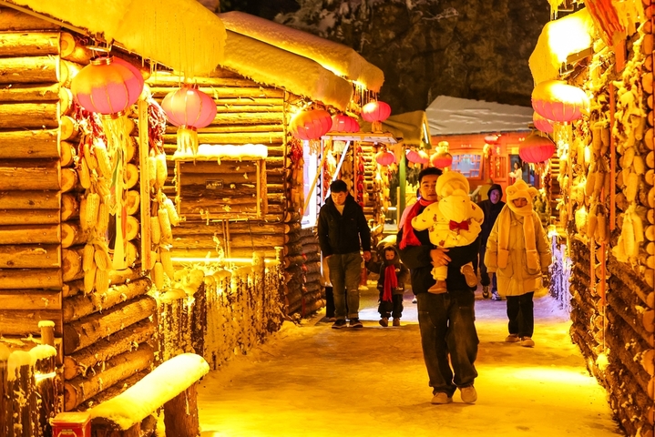 1月7日晚，贵州省六盘水市，游客在“南国雪乡”项目内游玩。该项目凭借梅花山滑雪场的核心优势，以“厚雪压木屋、红灯映炊烟”为设计理念打造，让南方民众邂逅地道雪乡风情。（无人机照片）  
