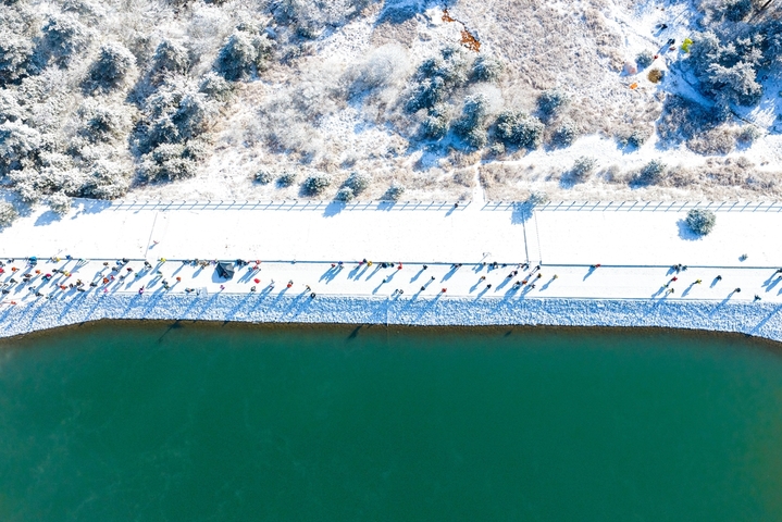 2026年1月21日，杭州临安百丈岭迎来雪后晴天，群山银装素裹，湖水碧蓝如镜，游客沿湖赏雪、拍照、露营，尽享高山雪景与自然静谧之美。