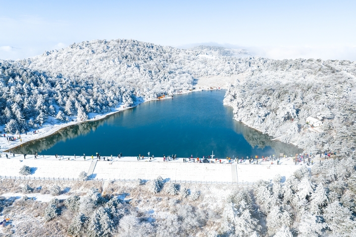 2026年1月21日，杭州临安百丈岭迎来雪后晴天，群山银装素裹，湖水碧蓝如镜，游客沿湖赏雪、拍照、露营，尽享高山雪景与自然静谧之美。