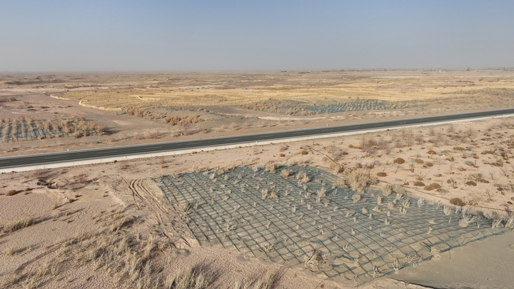 2026年1月22日，在甘肃省酒泉市金塔至大墩门公路两侧连绵起伏的沙丘上，千亩阻沙网与草方格交织成一道道的 “沙海防线”，昔日随风移动的沙丘被牢牢锁住。

