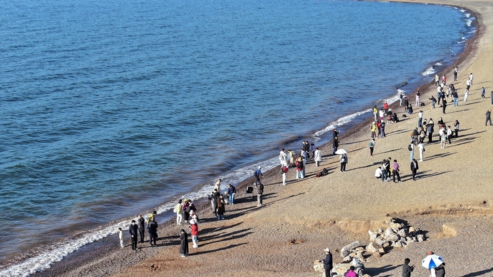 2026年1月29日，在云南省玉溪市抚仙湖沙滩，众多游客在赏景游玩。