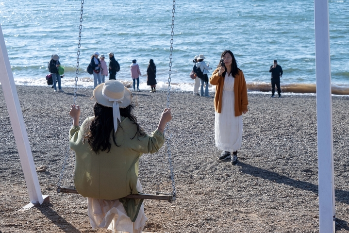 2026年1月29日，在云南省玉溪市抚仙湖沙滩，众多游客在赏景游玩。