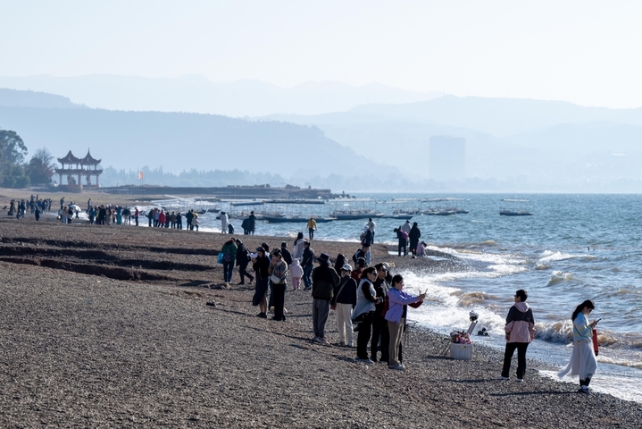2026年1月29日，在云南省玉溪市抚仙湖沙滩，众多游客在赏景游玩。