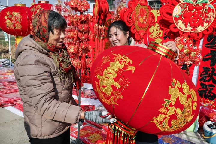 2026年2月2日，小朋友在江苏省连云港市赣榆区墩尚镇乡村大集上选购自己喜欢的春节饰品。
