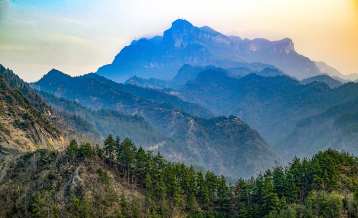 2026年3月13日，重庆，酉阳土家族苗族自治县丁市镇沙溪村，红日跃出群山，薄雾轻笼村落。蜿蜒山道串起层层梯田，袅袅炊烟随霞光升腾，与田间新绿、林间繁花相映。晨光漫过青瓦屋舍，唤醒沉睡的山乡，勾勒出一幅充满烟火气的渝东南春日晨景，尽显乡村田园的诗意与生机。