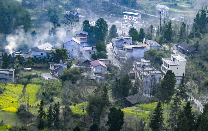 2026年3月13日，重庆，酉阳土家族苗族自治县丁市镇沙溪村，红日跃出群山，薄雾轻笼村落。蜿蜒山道串起层层梯田，袅袅炊烟随霞光升腾，与田间新绿、林间繁花相映。晨光漫过青瓦屋舍，唤醒沉睡的山乡，勾勒出一幅充满烟火气的渝东南春日晨景，尽显乡村田园的诗意与生机。何毅/IC photo