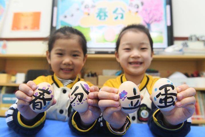 2026年3月19日，河北石家庄，新乐市市直第三幼儿园的两小朋友在展示写着“春分立蛋”的手绘彩蛋。春分节气将至，我国有“春分到，蛋儿俏”的谚语，民间有“春分立蛋”习俗。据史料记载，“春分立蛋”的传统起源于4000年前，意在庆祝春天的来临。

