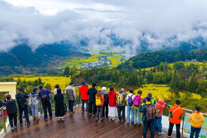 2026年3月27日，江西婺源江岭景区云雾缭绕，万亩梯田油菜花海金浪翻涌，白墙黛瓦的村落若隐若现，宛如一幅流动的水墨长卷。春日的江岭，以花为墨、以山为纸，绘就出中国最美乡村的诗意画卷，吸引八方游客共赴这场春天的盛宴。