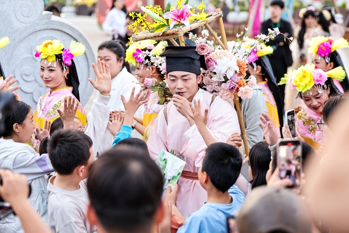 2026年4月25日，在甘肃省陇南市武都区万象街，“背花郎”NPC与孩子互动。